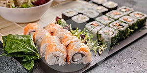 Asian Food banner. Philadelphia roll with salmon and rolls with vegetables on a black stone board. Chinese cuisine. Selective