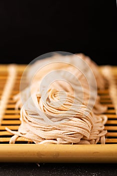 Asian Food concept homemade uncook oriental egg noodles on bamboo tray with copy space