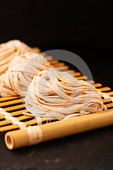 Asian Food concept homemade uncook oriental egg noodles on bamboo tray with copy space