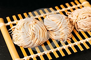 Asian Food concept homemade uncook oriental egg noodles on bamboo tray with copy space