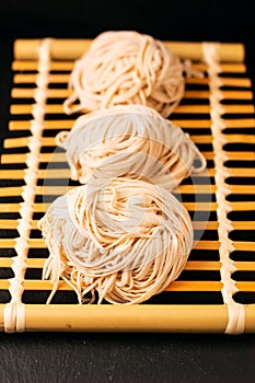 Asian Food concept homemade uncook oriental egg noodles on bamboo tray with copy space