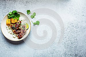 Asian food concept. Sticky sesame chicken with rice and vegetables in white plate, gray background, top view, copy space