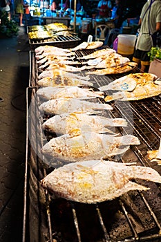 Asian food. Counter with fish in salt on the grill at a night food street market