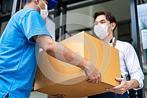Asian food deliver man wear face mask in blue uniform handling parcel box, carrying the package to waiter in coffeehouse. Postman
