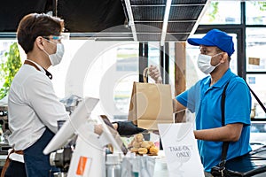 Asian Food delivery man receive beverage order from restaurant worker. Waiter wearing protective mask due to Covid-19 pandemic,