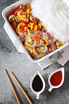 Asian food: fried chicken with tricolor bell peppers and rice vermicelli