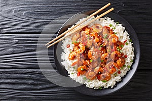 Asian food fried shrimp with garlic, chili pepper, sesame seeds and green onions served with rice close-up. Horizontal top view