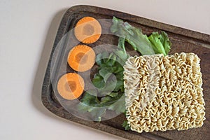 Asian food instant noodle has vegetable ingredient on pink wood table