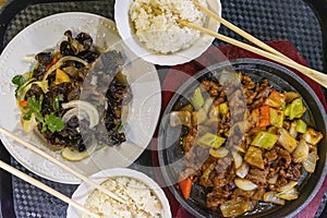 Asian food, roast meat and rice with chopsticks in the bowl, vegetables and mushroom, top view. Gastronomic gourmet