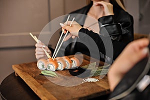 Asian food-sushi, chopsticks and knife. woman in black suit.