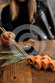 Asian food-sushi, chopsticks and knife. woman in black suit.