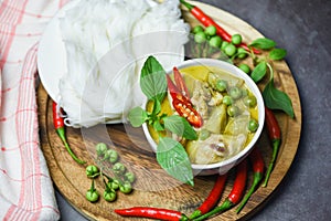 Asian food on the table - Thai food green curry chicken on soup bowl and thai rice noodles vermicelli with ingredient herb