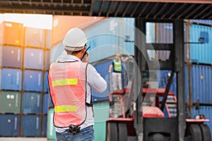 Asian foreman logistic staff loading containers box from Cargo freight ship at Cargo container shipping