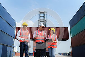 Asian foreman walking and explaining the various operations in the container depot terminal to worker