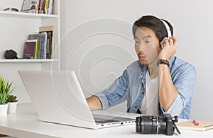 Asian Freelance Videographer Testing Multimedia Sound by Laptop in Home Office