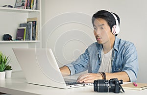 Asian Freelance Videographer Work from Home Checking Multimedia Sound by Laptop in Home Office