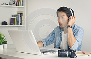 Asian Freelance Videographer Work from Home Testing Multimedia Sound by Laptop in Home Office in Vintage Tone