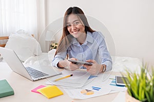 Asian freelancer looking at camera and holding tablet while work