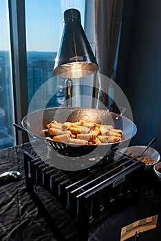 Asian fried eggrolls dish being cooked on the stove under a light near the window photo