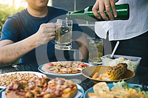 Asian friends are helping to pour beer into the bottle of his partner and have fun together in celebration