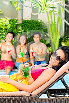 Asian friends partying at pool party in resort