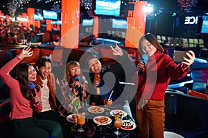 Asian friends singing at karaoke club and make selfie