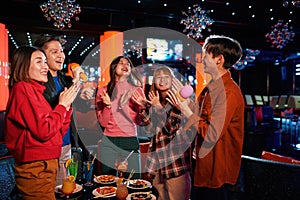 Asian friends singing into microphone at karaoke party at club