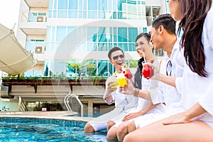 Asian Friends sitting by hotel swimming pool