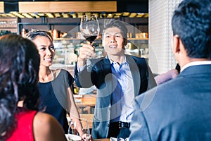 Asian friends toasting with red wine in bar