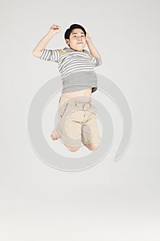 Asian funny child boy jumping on gray background