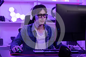 Asian gamer with a happy expression in front of a computer screen, lokking in computer screen and concentrate with online video