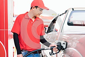 Asian gas station worker man filling high energy power fuel in auto car tank in petrol station, commercial service for benzine,