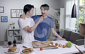 Asian gay couple cooking on kitchen.LGBT men couple are having fun together while preparing healthy food.Healthy lifestyle concept