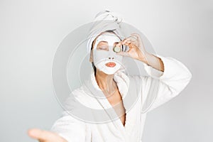 Asian girl applying facial clay mask. Beauty treatments. Over white background.