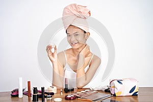 asian girl applying facial moisturizer while holding jar