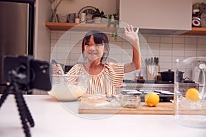 Asian Girl Baking Cupcakes In Kitchen At Home Whilst On Vlogging On Mobile Phone photo