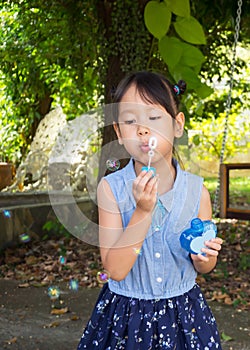 Asian girl blowing bubbles. Funny activity. Natural acting. Gar