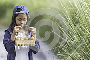 An Asian girl is carrying a basket containing eggs