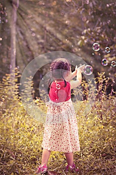 Asian girl catches soap bubbles on nature background. Outdoors.