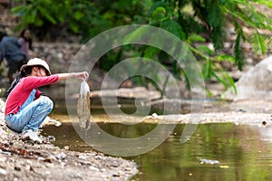 Asian girl collecting garbage and plastic on the river to dumped into the trash.