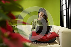 Asian girl with computer sitting on sofa at home