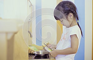 Asian girl cooking in toy kitchen