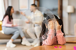 Asian Girl Crying Covering Eyes While Parents Having Quarrel Indoor