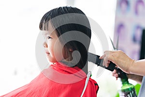 Asian girl cut hair at beauty salon. The hairdresser`s hand gently brushes the hair with skill.