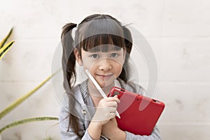 Asian girl with digital tablet and pen studying online at home.