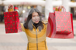 Asian girl enjoying Christmas shopping - young happy and beautiful Chinese woman holding red shopping bag buying presents at