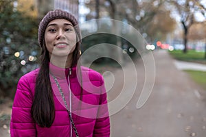 Asian girl with freckles and unusual appearance. Attractive girl in a pink jacket and Knitted hat. Blurred background