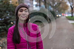 Asian girl with freckles and unusual appearance. Attractive girl in a pink jacket and Knitted hat. Blurred background