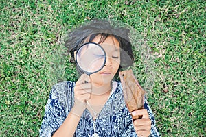 Asian girl hand holding magnifying glass in garden