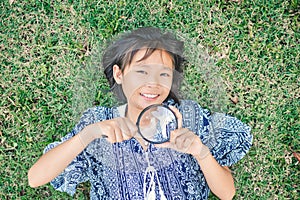 Asian girl hand holding magnifying glass in garden